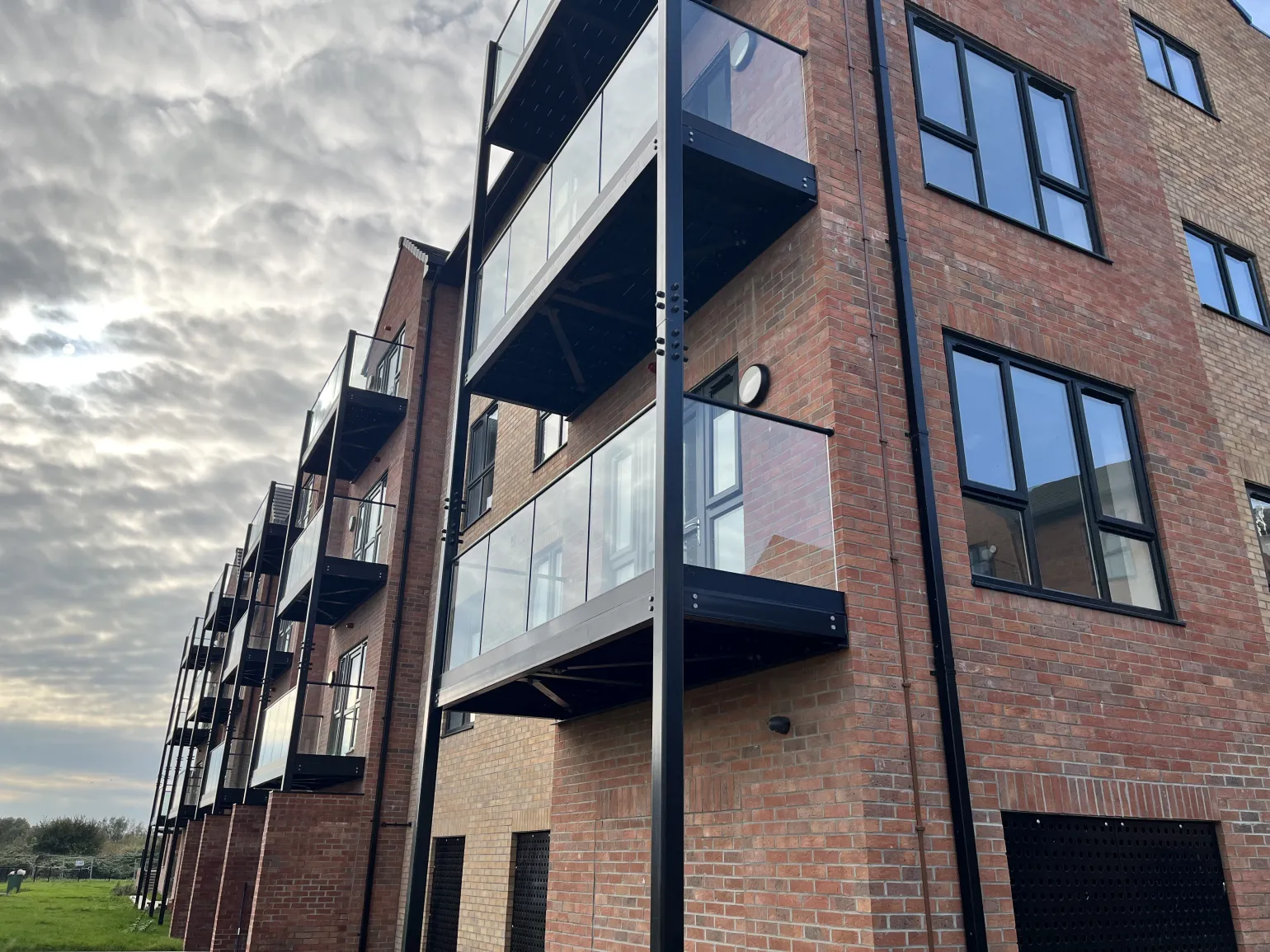 Dry-glazed, two-sided screw-clamp technology securely holds the glass in place and allows for precise on-site adjustments, enabling installers to fine-tune glass alignment without the use of sealants or specialist tools.

The result is a balcony design with striking black detailing that complements the overall modern styling of this attractive riverside development, and fall protection to ensure the on-going safety and comfort of all residents.
